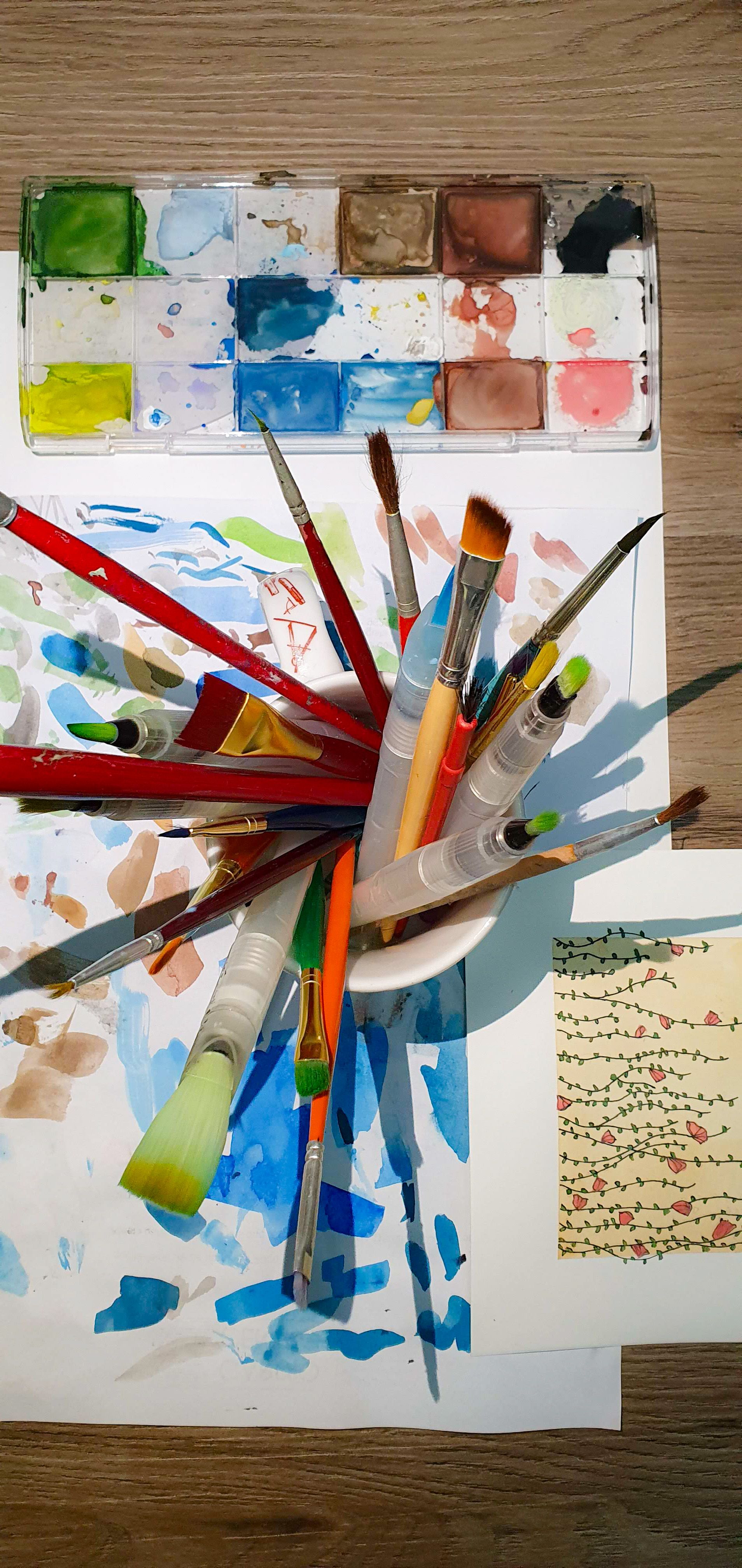 Malutensilien und selbstgemalte Bilder. Foto: Ana Carolina Miliani/Pexels – Ana Carolina Miliani/Pexels